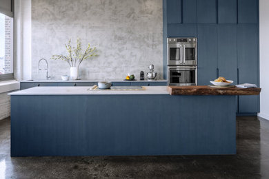 Inspiration for a large contemporary single-wall cement tile floor and black floor open concept kitchen remodel in New York with a farmhouse sink, flat-panel cabinets, blue cabinets, quartz countertops, gray backsplash, cement tile backsplash, stainless steel appliances, an island and gray countertops