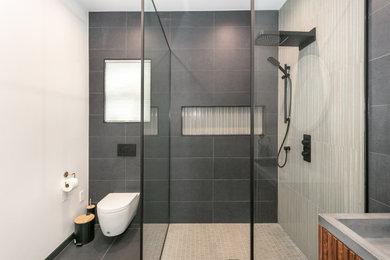 Example of a mid-sized minimalist gray tile and porcelain tile porcelain tile, gray floor and single-sink bathroom design in Los Angeles with dark wood cabinets, a wall-mount toilet, white walls, a trough sink and a floating vanity