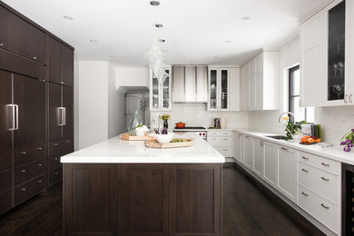 Large transitional l-shaped separate kitchen in Toronto with with island, white cabinets, white splashback, panelled appliances, dark hardwood floors, brown floor, white benchtop, a single-bowl sink and subway tile splashback.