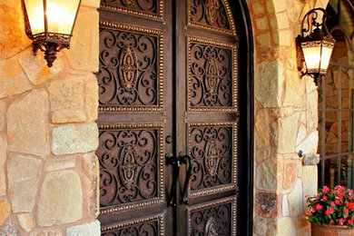 Inspiration for a mediterranean limestone floor entryway remodel in Austin with yellow walls and a brown front door