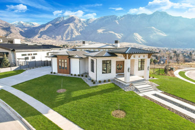 This is an example of a large and white modern bungalow detached house in Salt Lake City with mixed cladding, a hip roof, a mixed material roof, a black roof and shiplap cladding.