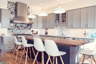 Inspiration for a large transitional l-shaped light wood floor and brown floor eat-in kitchen remodel in Cedar Rapids with a single-bowl sink, shaker cabinets, gray cabinets, wood countertops, white backsplash, subway tile backsplash, stainless steel appliances and an island