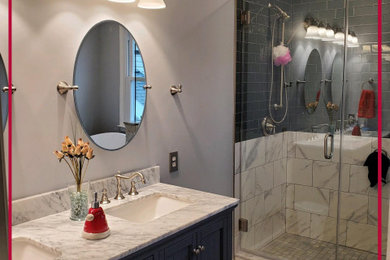 Large transitional master gray tile and glass tile ceramic tile and brown floor bathroom photo in Philadelphia with blue cabinets, an undermount sink, marble countertops, a hinged shower door and white countertops