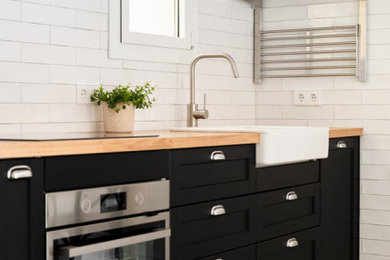 Inspiration for a country kitchen remodel in Los Angeles with a farmhouse sink, shaker cabinets, black cabinets, wood countertops and stainless steel appliances