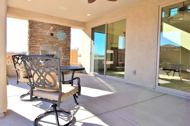 Inspiration for a backyard concrete patio remodel in Phoenix with a fireplace and a roof extension