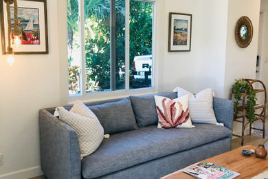 Small beach style open concept porcelain tile and beige floor living room photo in Other with white walls and a wall-mounted tv