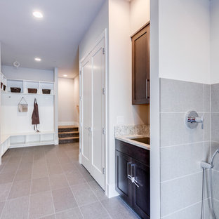 シアトルの大きいコンテンポラリースタイルのおしゃれな家事室 (アンダーカウンターシンク、シェーカースタイル扉のキャビネット、濃色木目調キャビネット、御影石カウンター、白い壁、磁器タイルの床、左右配置の洗濯機・乾燥機、グレーの床、マルチカラーのキッチンカウンター) の写真