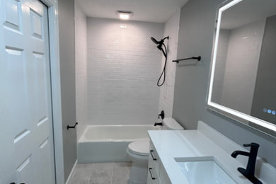 Bathroom - mid-sized kids' white tile and porcelain tile ceramic tile, gray floor and single-sink bathroom idea in Other with shaker cabinets, white cabinets, a two-piece toilet, gray walls, an undermount sink, quartzite countertops, white countertops and a freestanding vanity