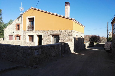 Ejemplo de fachada de casa rural de tamaño medio de dos plantas con revestimiento de piedra, tejado a dos aguas y tejado de teja de barro