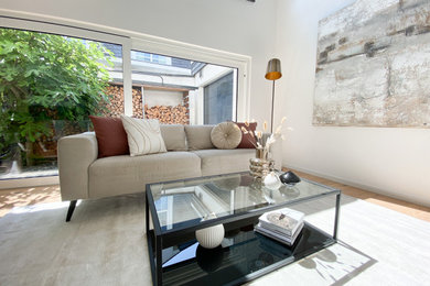 Großes Modernes Wohnzimmer mit beiger Wandfarbe, braunem Holzboden, Kaminofen, Kaminumrandung aus Stein und braunem Boden in Sonstige