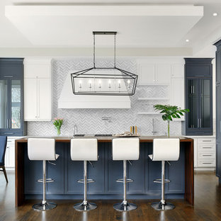 Diseño de cocina en L, tradicional renovada, grande, abierta, con armarios con paneles empotrados, puertas de armario azules, encimera de madera, salpicadero blanco, suelo de madera oscura, una isla, suelo marrón, fregadero encastrado, salpicadero de mármol y electrodomésticos de acero inoxidable