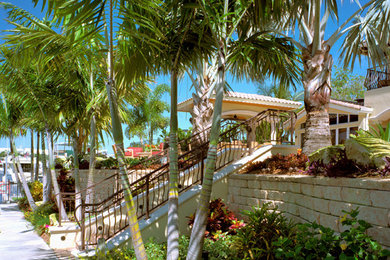 Design ideas for a large tropical backyard full sun formal garden for summer in Miami with natural stone pavers.
