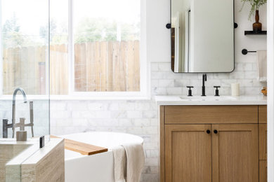 Example of a mid-sized master white tile and subway tile vinyl floor and double-sink bathroom design in Sacramento with recessed-panel cabinets, brown cabinets, white walls, an undermount sink, quartz countertops, a hinged shower door, white countertops and a built-in vanity