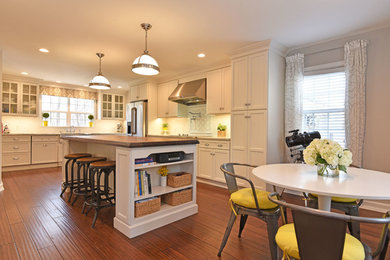 Inspiration for a large transitional l-shaped bamboo floor and brown floor eat-in kitchen remodel in Providence with a farmhouse sink, recessed-panel cabinets, white cabinets, marble countertops, white backsplash, ceramic backsplash, stainless steel appliances and an island