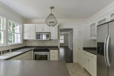 Eat-in kitchen - large transitional u-shaped ceramic tile eat-in kitchen idea in Birmingham with a double-bowl sink, raised-panel cabinets, white cabinets, beige backsplash, ceramic backsplash, stainless steel appliances, a peninsula and laminate countertops