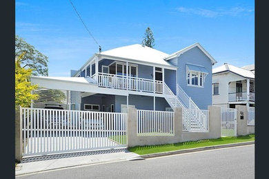 Photo of a large beach style two-storey blue house exterior in Brisbane with a hip roof, concrete fiberboard siding and a metal roof.