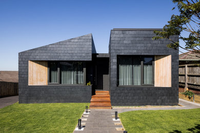This is an example of a mid-sized contemporary two-storey grey house exterior in Melbourne with a gable roof, a shingle roof, a black roof and shingle siding.