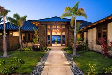 This is an example of a mid-sized tropical front door in Hawaii with beige walls, concrete floors, a double front door and a dark wood front door.