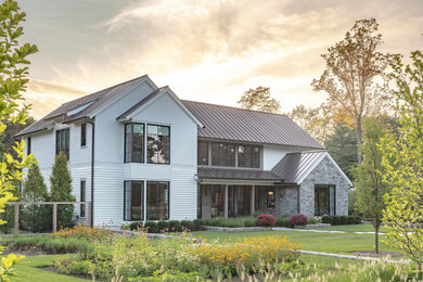 Стильный дизайн: двухэтажный, деревянный, белый частный загородный дом среднего размера в стиле модернизм с двускатной крышей, металлической крышей, серой крышей и отделкой планкеном - последний тренд