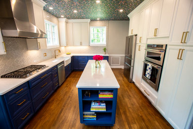 Inspiration for a mid-sized eclectic u-shaped medium tone wood floor, brown floor and wallpaper ceiling eat-in kitchen remodel in DC Metro with a farmhouse sink, recessed-panel cabinets, blue cabinets, quartz countertops, gray backsplash, porcelain backsplash, stainless steel appliances, an island and white countertops