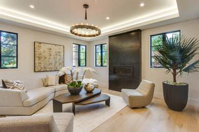 Example of a mid-sized eclectic open concept light wood floor and tray ceiling living room design in San Francisco with beige walls, a standard fireplace and a metal fireplace