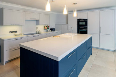 Eat-in kitchen - large modern ceramic tile and beige floor eat-in kitchen idea in Wilmington with an undermount sink, shaker cabinets, white cabinets, quartz countertops, black appliances, an island, white backsplash and white countertops