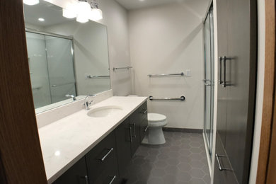 Sliding shower door - contemporary master porcelain tile, gray floor and single-sink sliding shower door idea with flat-panel cabinets, gray cabinets, a one-piece toilet, white walls, an undermount sink, quartz countertops, white countertops and a floating vanity