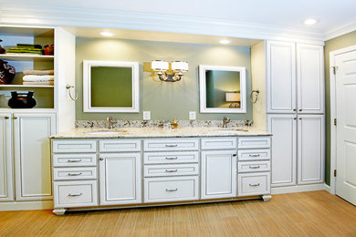 Design ideas for a large traditional master bathroom in St Louis with a drop-in sink, recessed-panel cabinets, white cabinets, granite benchtops, green walls and light hardwood floors.