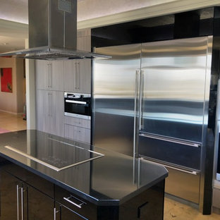 Große Moderne Küche in U-Form mit Vorratsschrank, Landhausspüle, flächenbündigen Schrankfronten, grauen Schränken, Granit-Arbeitsplatte, Küchenrückwand in Schwarz, Kücheninsel, schwarzer Arbeitsplatte, Keramikboden und beigem Boden in Miami