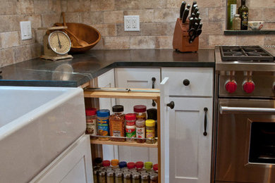 Inspiration for a mid-sized farmhouse l-shaped medium tone wood floor eat-in kitchen remodel in Chicago with a farmhouse sink, shaker cabinets, stainless steel appliances, white cabinets, soapstone countertops, stone tile backsplash and an island