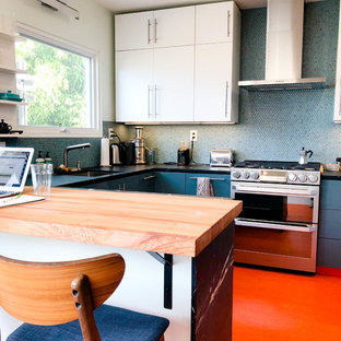 Medium sized modern u-shaped kitchen pantry in Los Angeles with a submerged sink, flat-panel cabinets, white cabinets, blue splashback, stainless steel appliances, lino flooring, a breakfast bar, orange floors, granite worktops, mosaic tiled splashback and black worktops.