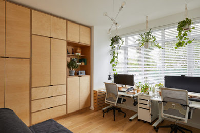 Immagine di un ufficio minimal di medie dimensioni con pareti bianche, pavimento in legno massello medio, scrivania autoportante e pavimento marrone