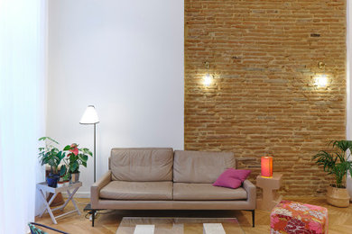 Réalisation d'un salon design avec parquet clair et un mur en parement de brique.