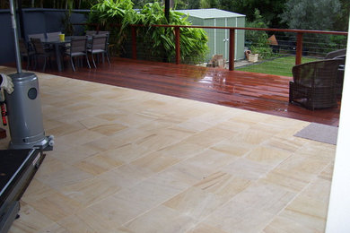 This is an example of a mid-sized modern backyard patio in Gold Coast - Tweed with natural stone pavers, a roof extension and a water feature.