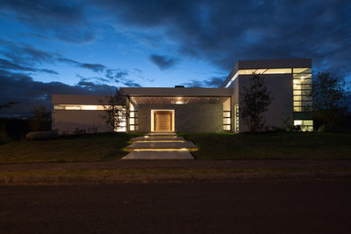 Diseño de fachada de casa beige contemporánea extra grande de tres plantas con revestimiento de piedra, tejado plano y tejado de varios materiales