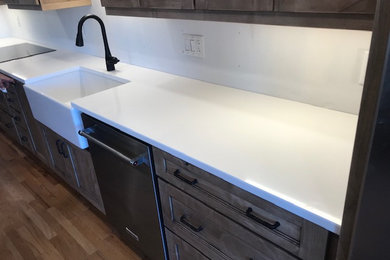 Example of a kitchen design in Charlotte with a farmhouse sink, quartz countertops, an island and white countertops