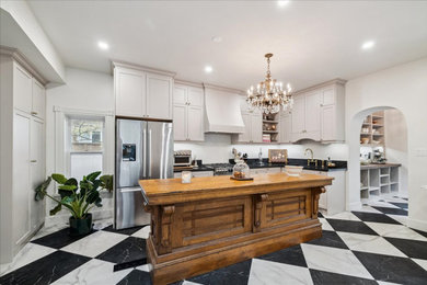 Inspiration for a large 1960s l-shaped multicolored floor and porcelain tile enclosed kitchen remodel in Toronto with an undermount sink, shaker cabinets, white cabinets, quartzite countertops, stainless steel appliances, an island and black countertops