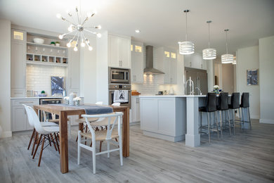 Open concept kitchen - large modern single-wall ceramic tile and gray floor open concept kitchen idea in Other with a single-bowl sink, shaker cabinets, gray cabinets, solid surface countertops, white backsplash, ceramic backsplash, stainless steel appliances, an island and white countertops