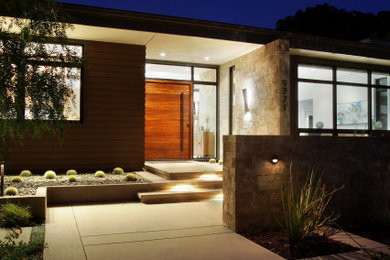 Inspiration for a large modern concrete floor, beige floor and vaulted ceiling entryway remodel in Orange County with beige walls and a medium wood front door