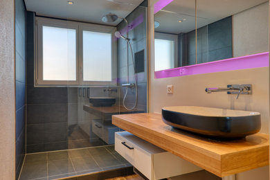 Mittelgroßes Modernes Badezimmer En Suite mit weißen Schränken, bodengleicher Dusche, Wandtoilette, schwarzen Fliesen, Keramikfliesen, Vinylboden, Aufsatzwaschbecken, Waschtisch aus Holz, braunem Boden, offener Dusche, brauner Waschtischplatte, Einzelwaschbecken und schwebendem Waschtisch in Sonstige