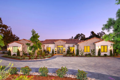 Expansive contemporary one-storey grey house exterior in San Diego with stone veneer and a shingle roof.