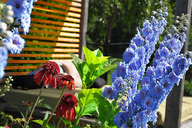 Modelo de jardín rural pequeño en verano en patio trasero con jardín francés, exposición total al sol y entablado