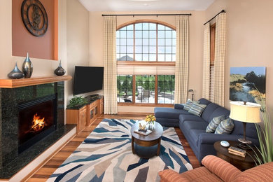 Inspiration for a mid-sized transitional open concept medium tone wood floor and brown floor family room remodel in Milwaukee with beige walls, a standard fireplace, a tile fireplace and a wall-mounted tv