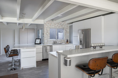 Eat-in kitchen - large mid-century modern u-shaped light wood floor eat-in kitchen idea in Los Angeles with an undermount sink, flat-panel cabinets, white cabinets, quartz countertops, white backsplash, stainless steel appliances and a peninsula