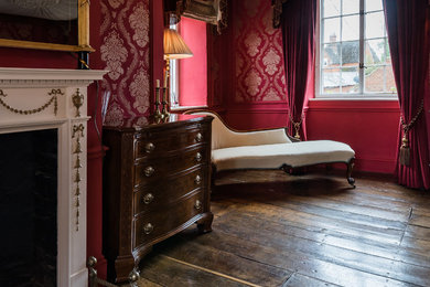 Diseño de dormitorio principal clásico de tamaño medio con paredes rojas, suelo de madera oscura, chimenea lineal, marco de chimenea de madera y suelo marrón