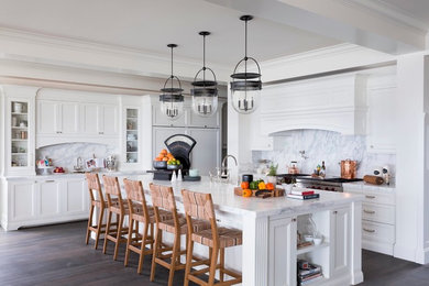 Photo of a beach style kitchen in Los Angeles with shaker cabinets, white cabinets, white splashback, white appliances, dark hardwood floors and with island.
