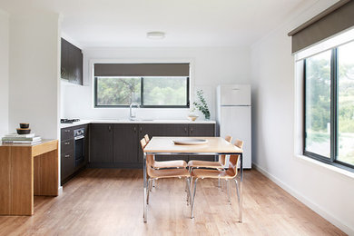Design ideas for a small contemporary kitchen in Melbourne with a double-bowl sink, glass sheet splashback, white appliances and light hardwood floors.