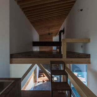 Esempio di una camera da letto stile loft etnica di medie dimensioni con pareti bianche, parquet scuro, stufa a legna, cornice del camino in cemento e pavimento marrone