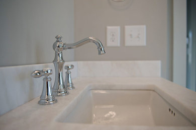 Inredning av ett badrum, med vita skåp, en dusch/badkar-kombination, vit kakel, tunnelbanekakel, grå väggar och mosaikgolv