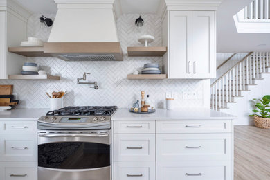 Example of a transitional l-shaped vinyl floor and gray floor eat-in kitchen design in Vancouver with a farmhouse sink, shaker cabinets, white cabinets, quartzite countertops, white backsplash, marble backsplash, stainless steel appliances, an island and white countertops